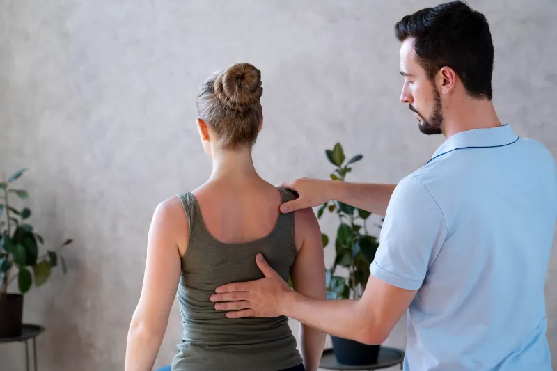 Physiotherapist examining patient's back for back pain treatment.