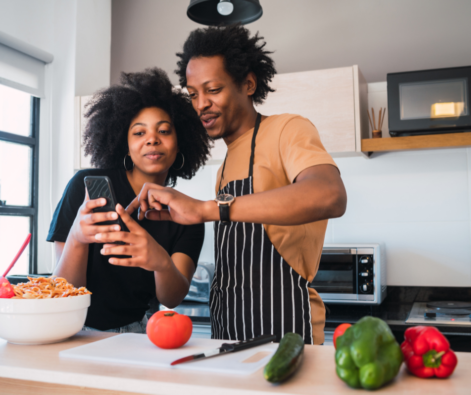 Couple in kitchen looking at smartphone, planning healthy meals and nutrition.